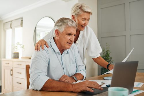 Foto: Zwei Pensionisten beim Esstisch mit einem Laptop